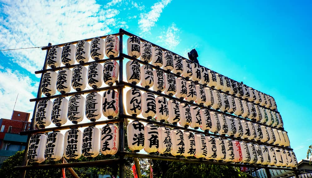 Tiers of white paper lanterns at Asakusa temple in Tokyo, each inscribed in black kanji with the name of a donor