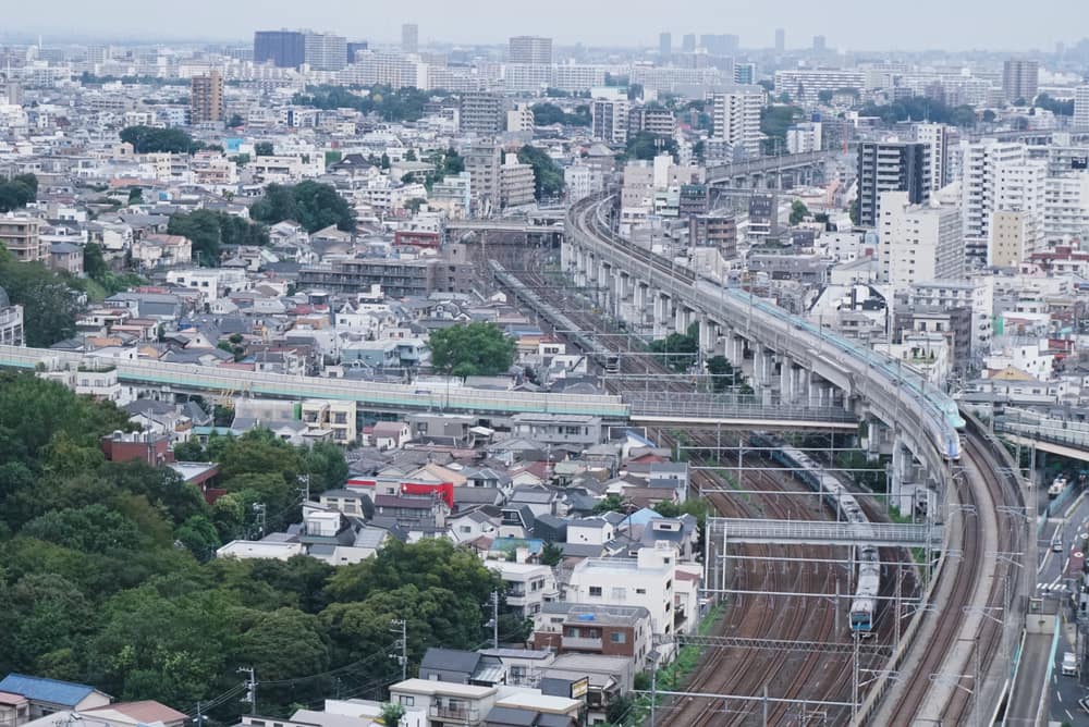 Bullet trains and railway lines curving through dense Tokyo neighbourhoods, seen from above