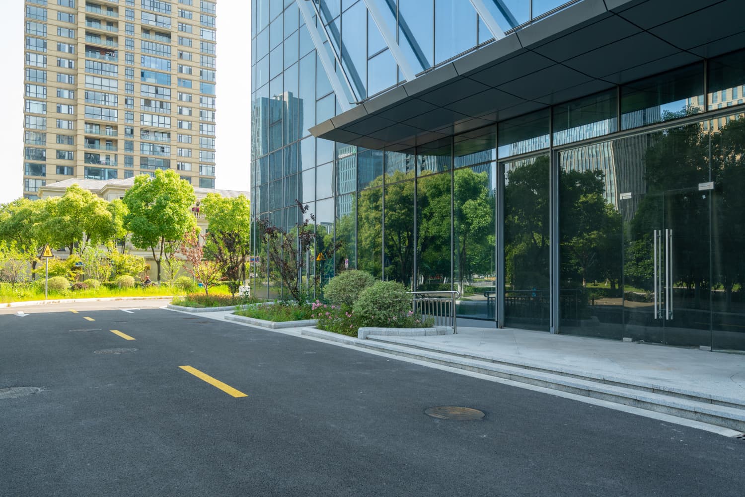 Road curving past a glass office building with a tower behind