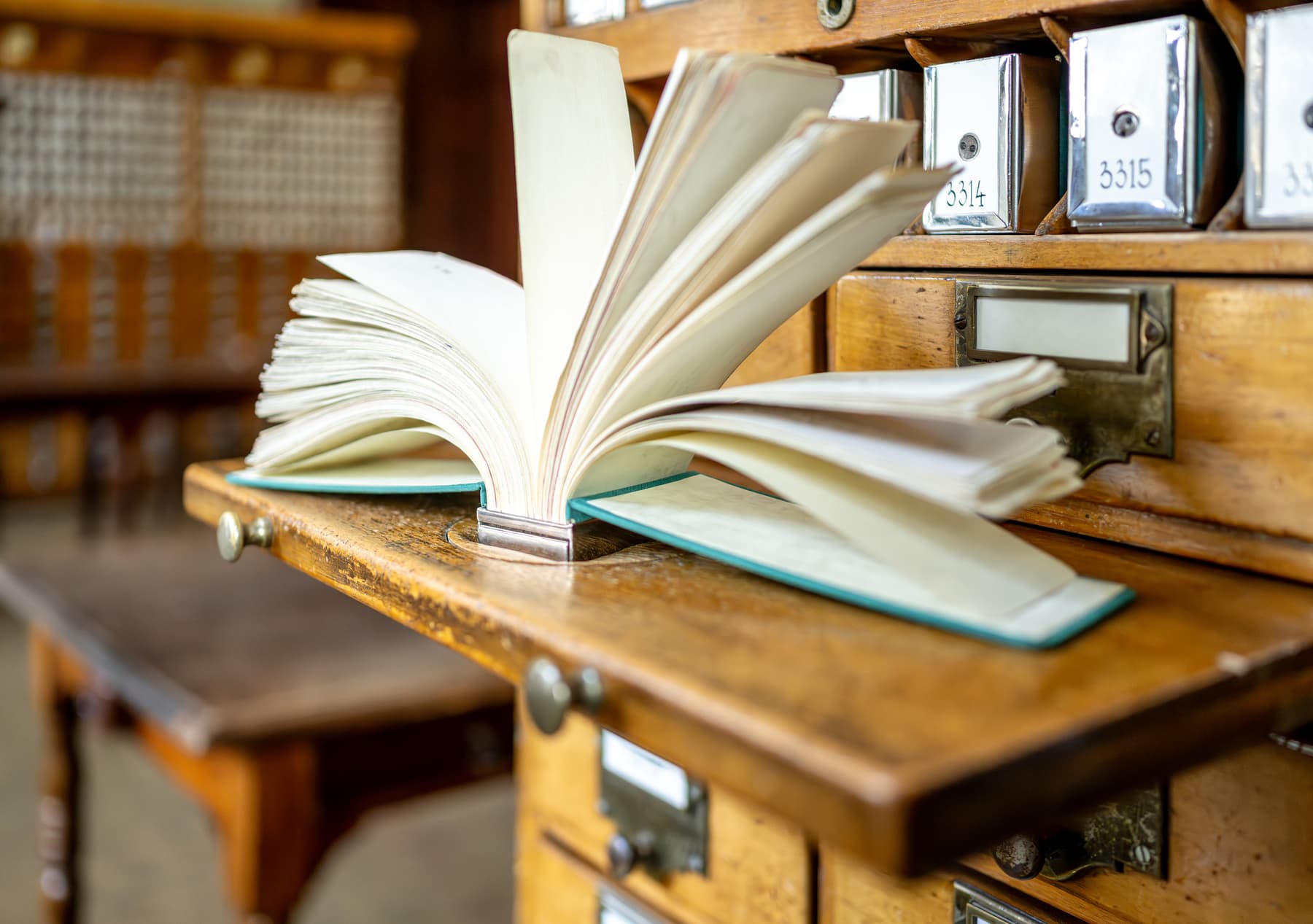 Open ledger on a wooden desk beside a wooden card index cabinet