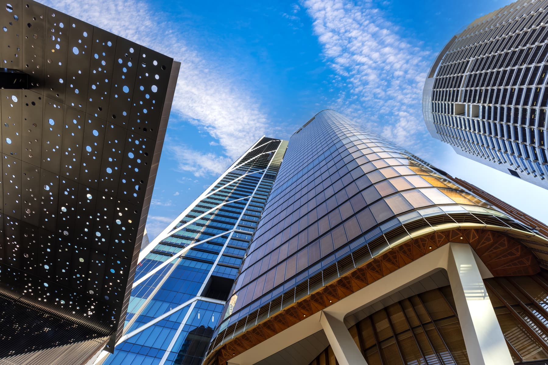 Curved glass office towers seen from street level against a blue sky