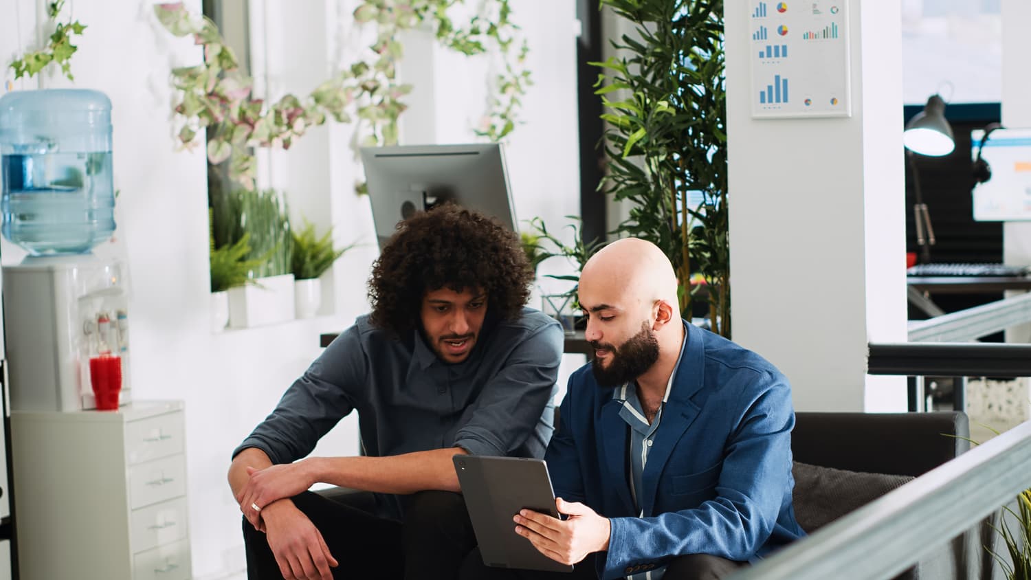 Team reviewing reports together on a tablet in an open-plan office