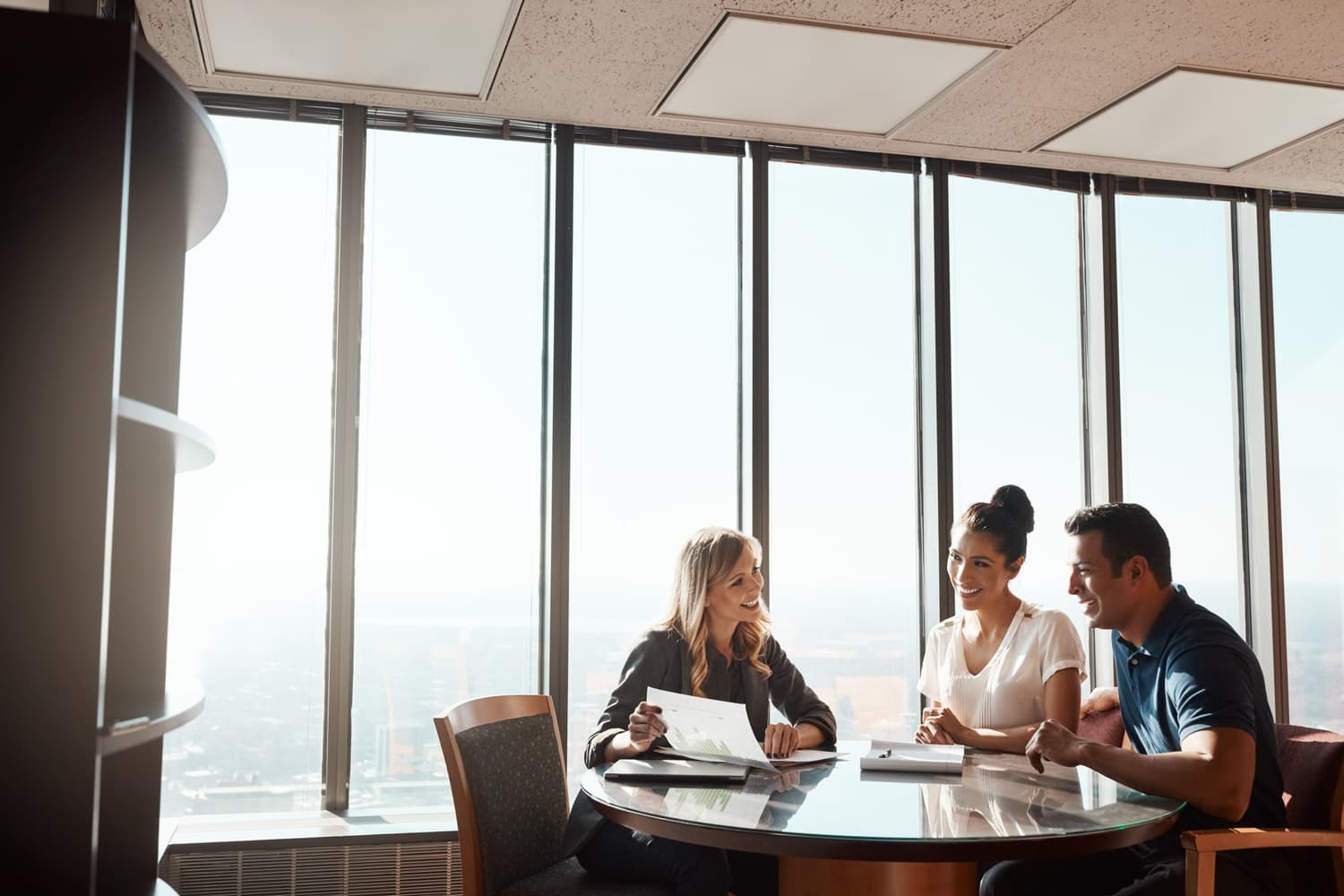 Adviser going through paperwork with two clients across a table