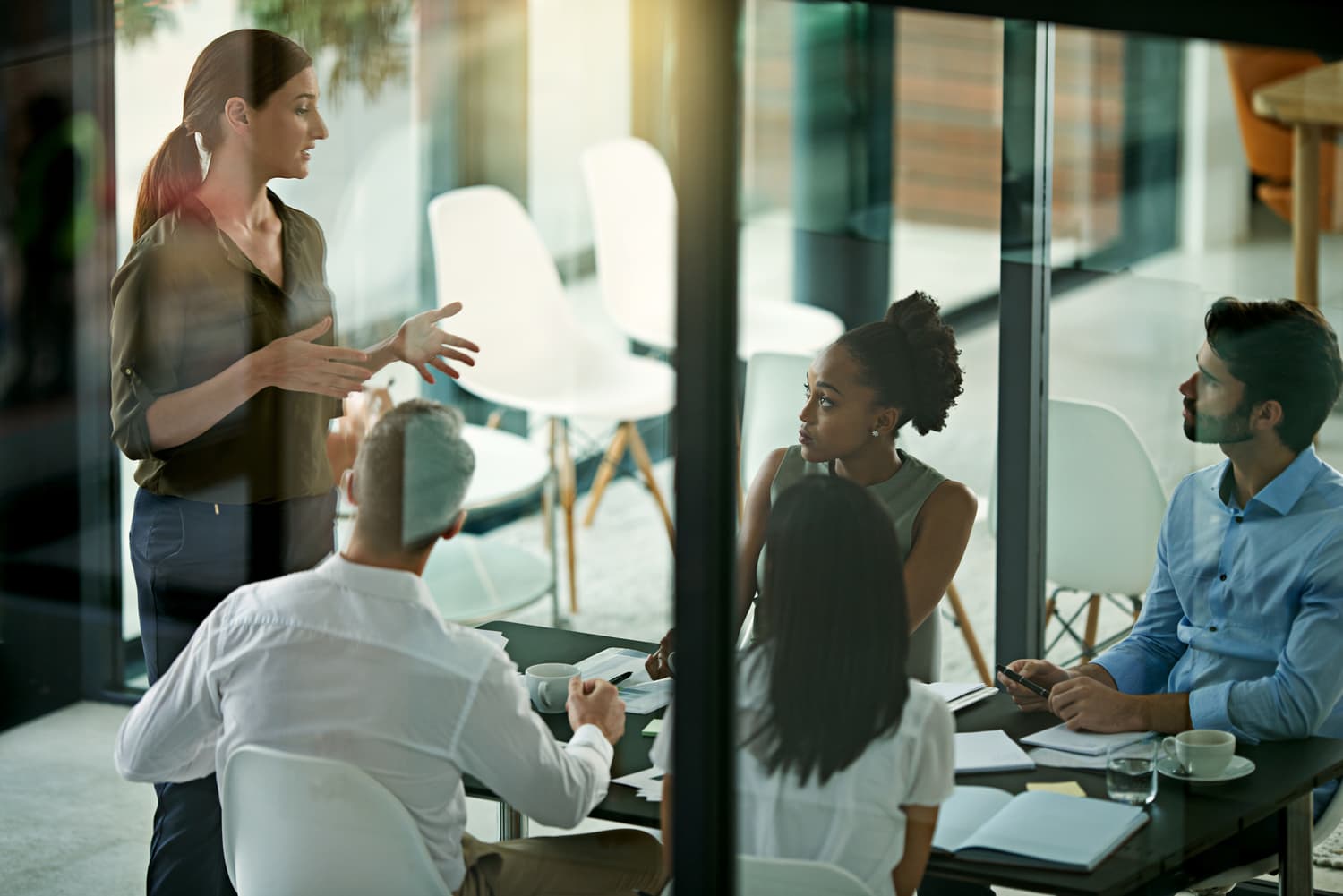 Colleagues listening to a speaker presenting in a boardroom