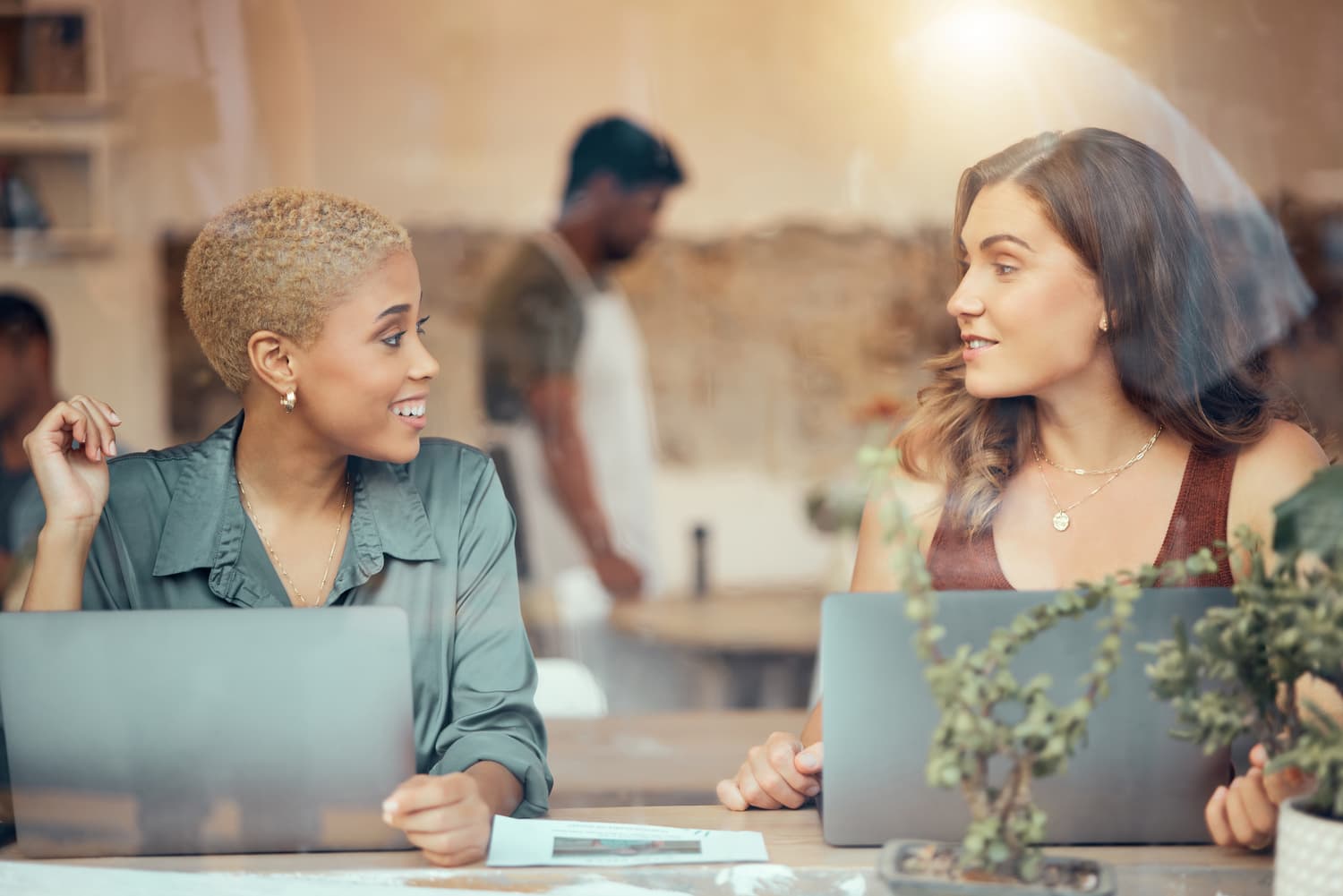 Two people meeting over a laptop and notes in a cafe